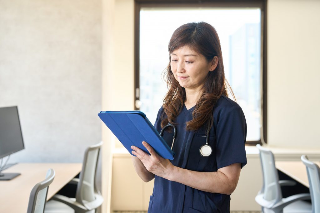 電子カルテをタブレットでみる女性医師